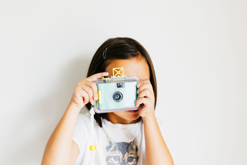 A little girl holding up a digital camera