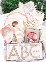 A pink theme birthday party bash box for little kids including paper plates, cups, napkins, a crown, birthday candle, and more